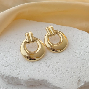 Fashionable gold geometric hoop earrings with vertical textured clasps on stone