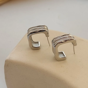 Modern silver C-shaped geometric hoop earrings with layered textured stripe design