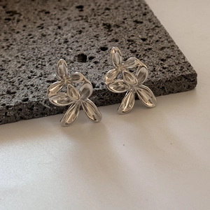 Dettaglio degli orecchini a fiore in argento lucido presentati su roccia vulcanica scura