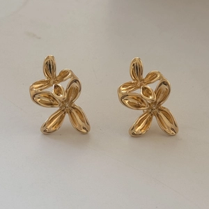 Dettaglio macro di orecchini a petali 3D dorati con design floreale in metallo lucido