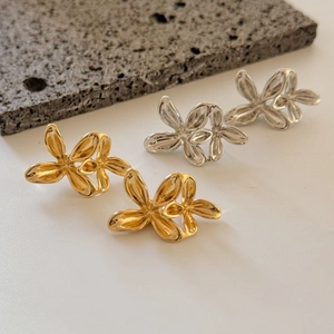 Dettaglio degli orecchini a fiore 3D in oro e argento su pietra vulcanica nera