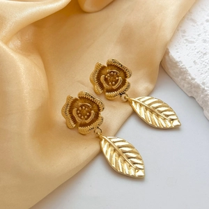 Detail of gold floral leaf drop earrings with intricate vein textures on silk fabric