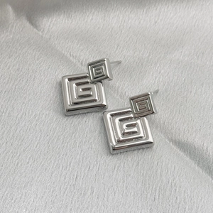 Silver square geometric earrings with swirl maze pattern on grey silk background