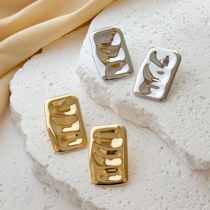 Minimalist wrinkled metal square stud earrings in gold and silver finish on white stone