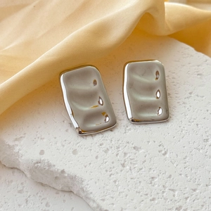 Polished silver wave texture rectangular stud earrings on elegant white marble base