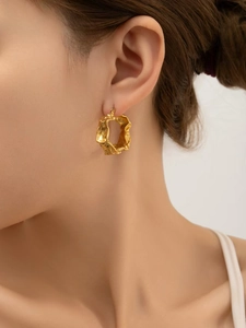 Detailansicht goldener Lava-Ohrring mit unregelmäßiger Textur am Model getragen
