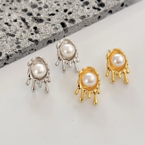 Detail of irregular liquid metal pearl studs in gold and silver finishes on stone