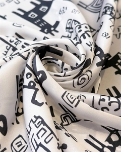 Macro shot of silk square scarf featuring artistic black prints on smooth white fabric