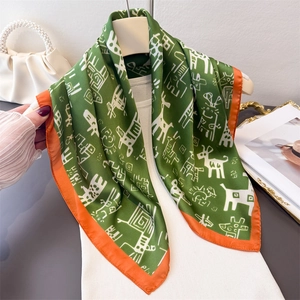 Elegant emerald silk scarf with animal print and orange trim hanging on a hanger