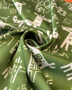 Close-up of green silk scarf featuring abstract patterns and smooth satin texture