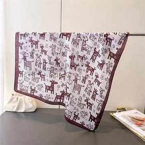Detail of a white silk scarf with dark brown giraffe prints draped over a metal rod