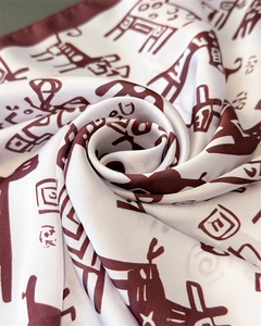 Close-up of elegant silk scarf with red abstract prints and glossy satin texture folds