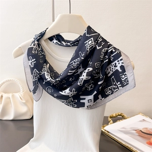 Close-up of black and white printed silk scarf styled on a white top with abstract patterns