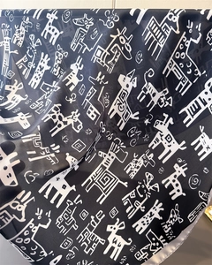 Detailed texture of black silk scarf featuring white geometric giraffe and spiral patterns