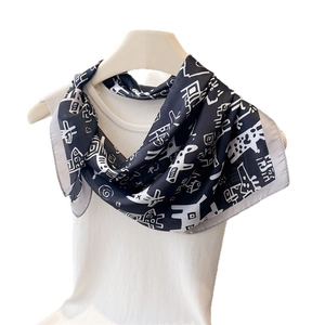Elegant black and white printed silk scarf with abstract tribal patterns on white vest