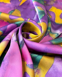 Gros plan sur un foulard en soie de luxe avec des motifs abstraits violets et dorés