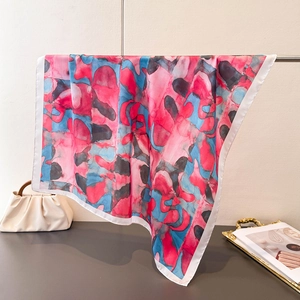 Détail d'un foulard carré en soie avec imprimé à l'encre rose et bleu sur un support