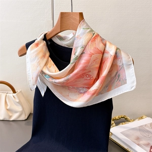 Detail of floral silk scarf with pink and orange flowers on black sleeveless knitwear