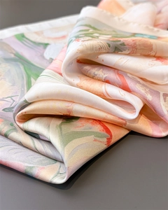 Macro detail showing smooth silk texture and soft floral print on this chic women's scarf