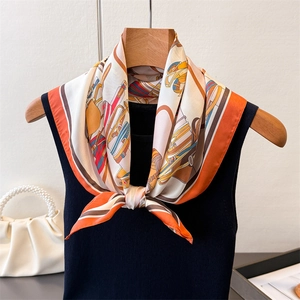Elegante foulard di seta arancione con motivo equestre annodato su un top nero senza maniche