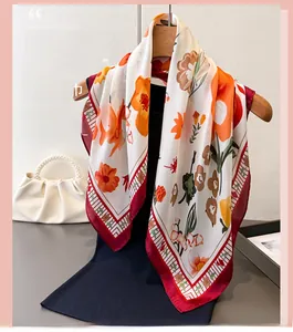 Detail of silk-like scarf with orange floral print and pearl handle bag accessory