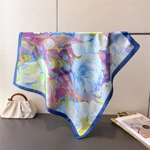 Detail of silk-like scarf with abstract floral prints and navy blue borders on a metal rod