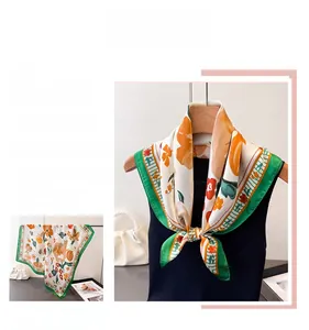 Detail of silk square scarf featuring orange floral patterns and green stripe borders
