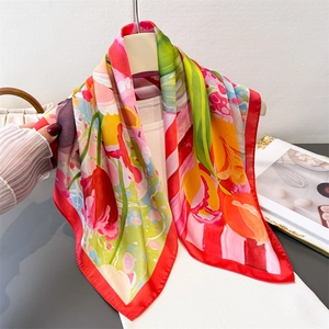 Detailed view of large floral print silk scarf with bright tulips on white knitwear