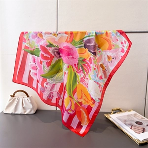 Floral silk-like square scarf in red and yellow draped on a metal display rack