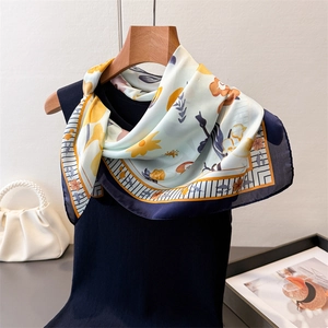 Detailed close-up of floral silk scarf draped on a wooden hanger with luxury props