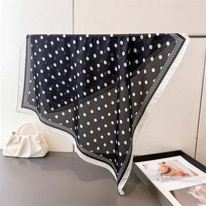 Elegant black and white polka dot silk scarf hanging on a metal stand with satin finish