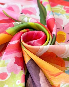 Close-up of vibrant floral print silk scarf featuring a detailed spiraled fabric texture