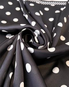 Macro shot of silky satin fabric with classic white polka dots on a black background