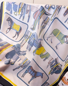 Dettaglio ravvicinato di un foulard in seta con motivi equestri di cavalli e selle