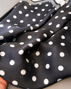 Detailed view of silk-like fabric featuring black and white polka dots with checkered edges