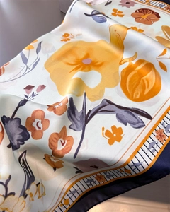 Detail of floral silk scarf showing satin texture with artistic flower prints and blue border