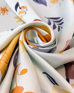 Close-up of floral silk satin scarf fabric showing soft texture and glossy floral patterns