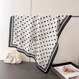 Elegant black and white polka dot silk-like square scarf draped on a display stand
