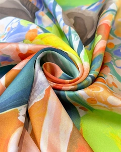 Close-up of silk scarf showing abstract colorful print and smooth satin texture
