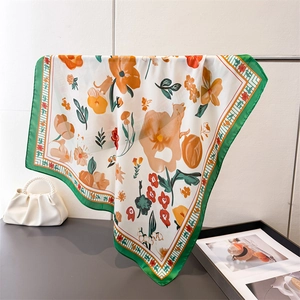 Detail of silk square scarf featuring floral prints, cat illustrations and green borders