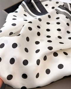 Close-up of silky geometric polka dot square scarf with elegant draped texture