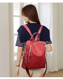 Detail of red oxford fabric backpack featuring silver zippers and stylish rivets