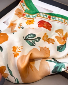 Detailed macro view of silk scarf texture with vibrant floral patterns and green borders