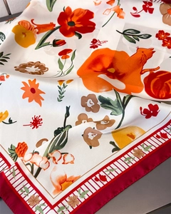 Detail of silk-like scarf with vibrant floral patterns, cat motifs, and red border trim