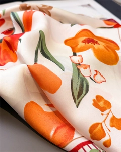 Detailed macro view of floral silk scarf featuring vibrant orange hand-painted flowers