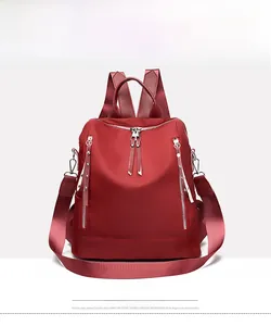 Front view of a burgundy waterproof nylon backpack with dual vertical zippers for women