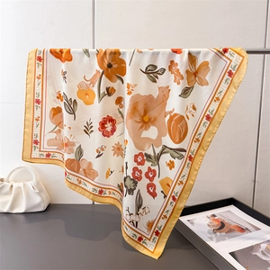 Close-up of silk square scarf with orange floral cat print and yellow striped border