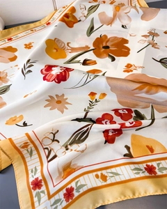 Macro detail of floral silk scarf showing elegant orange flower patterns and satin texture