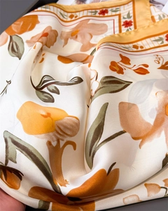 Detail of floral silk satin scarf showing smooth texture and elegant orange flower patterns