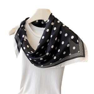 Elegant black and white polka dot silk scarf tied on a white top with geometric borders